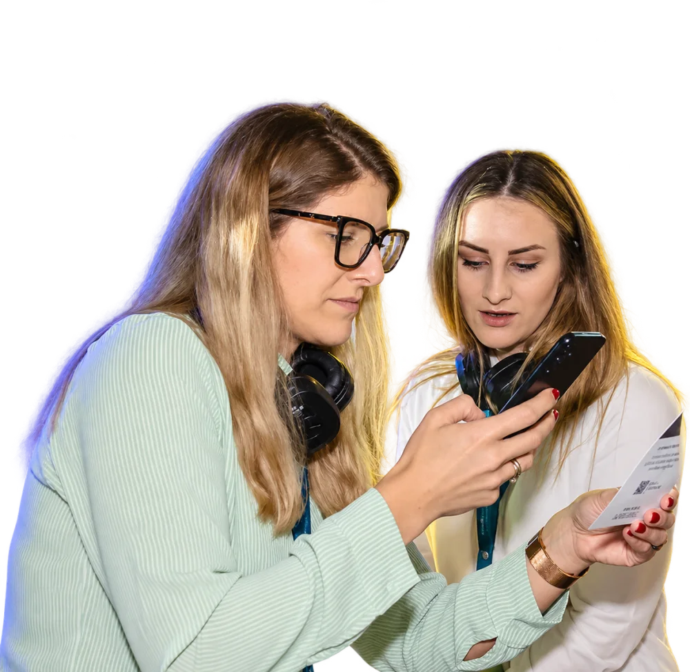 Duas participantes do Fórum ABRE 2026 olhando o app do evento no celular.